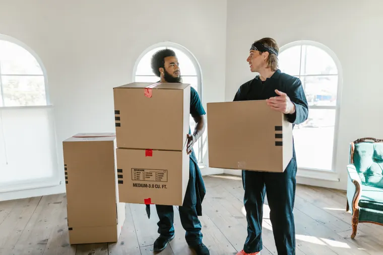 Crew members carrying boxes out of a cleared-out room during a household cleanout